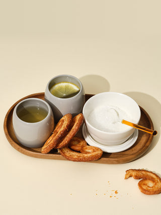 Two grey small cups with lemon tea next to a switch bowl with sugar on a small wooden tray