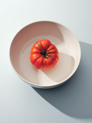 White bowl with red heirloom tomato in the center