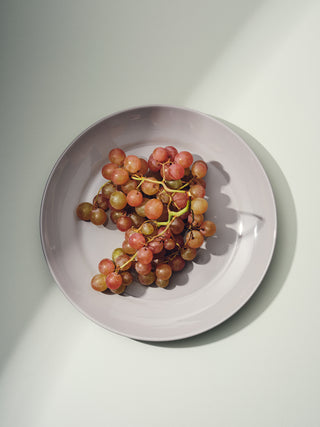 Grey dinner plate with a bunch of red grapes