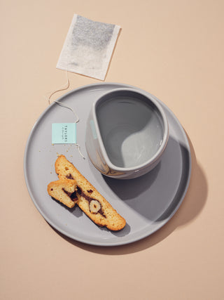 Grey cup and plate with a tea bag and biscotti