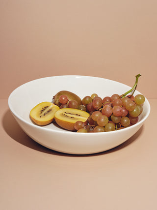 Serving bowl holding red grapes and halved kiwis