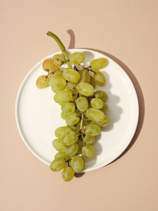 White plate with bunch of green grapes