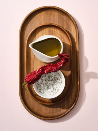 Switch bowl containing salt and a short pitcher containing oil on top of a wooden tray set