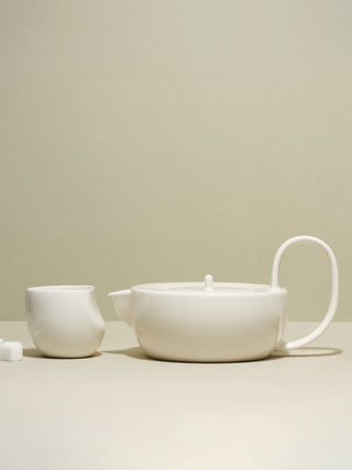 Large white teapot and medium white cup next to each other