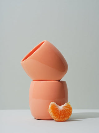 Coral ceramic cups stacked with a tangerine piece