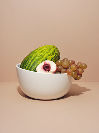 Deep serving bowl filled with watermelon, grapes and halved peaches