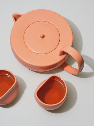 Large coral teapot next to two asymmetrical coral medium cups