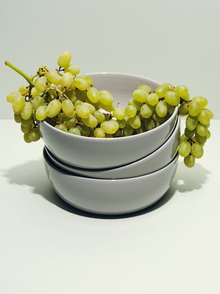 Stack of grey bowls with grapes arching over
