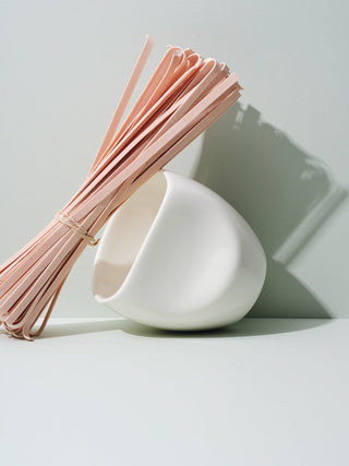 White asymmetrical cup tilted against dried pasta