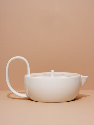 White ceramic teapot with large looping handle on its side