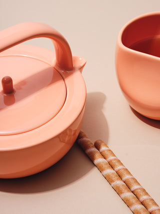 Small coral teapot and cup with biscuits