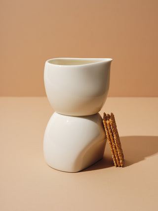 A white cup and creamer stacked with biscuits tilted on them
