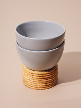 Two small gray bowls on top of a stack of crackers