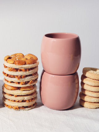 Short rose colored ceramic cups stacked next to towers of biscuits