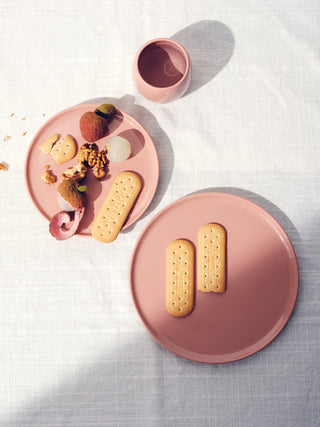 Top view of two different sized rose plates holding biscuits and lychees and a small cup